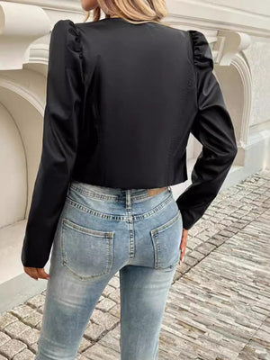 Black vegan leather bolero jacket with sculpted shoulders and long sleeves, styled with jeans.
