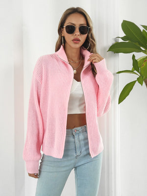 Ribbed knit zip-up sweater in blush pink with a high collar and silver zipper.