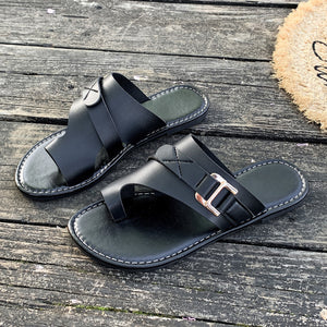 Black leather toe loop flat sandals with buckle detail and contrast stitching.