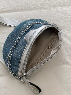 Crescent mini denim crossbody bag with silver chain detail and adjustable strap.