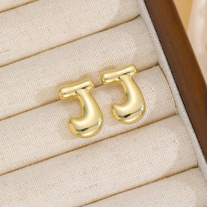 Gold sculptural stud earrings in the shape of the letter J