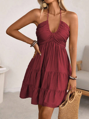 Burgundy ruched halter tiered mini dress with ruffles and a deep V-neckline.