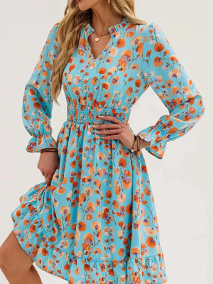 Pastel blue floral dress with smocked waist, ruffled neckline, and bell sleeves.