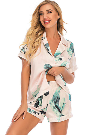 Blush pink satin pajama set with botanical print, button-up top and shorts.