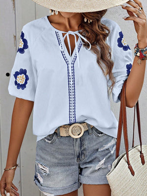 Light blue embroidered yoke sleeve blouse with tie neck and floral details.