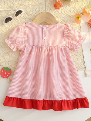 Baby dress in blush pink seersucker with white stripes, puff sleeves, and red ruffle hem.