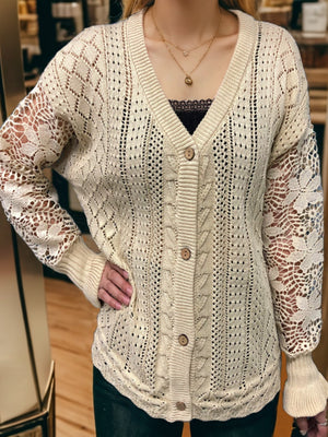 Tan knit cardigan with lace sleeves, V-neck, and button front.
