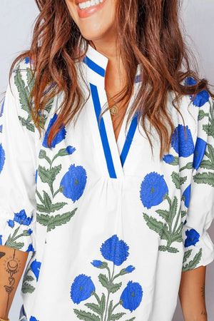 White cotton blouse with blue floral print, ruffled sleeves, and notched neckline.