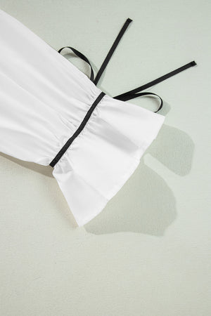 White blouse with black piped trim and tie detail on sleeve cuff
