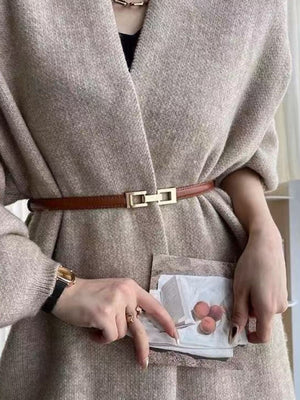 Brown cowhide leather belt with a gold buckle cinched over a tan cardigan.