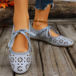 Sky blue floral cutout slip-on flats with tie detail and ankle strap.