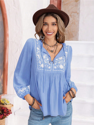 Misty Blue embroidered yoke blouse with gathered bodice, tie neck, and voluminous sleeves.