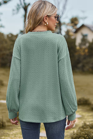 Light green cable knit pullover sweater with textured details and balloon sleeves.