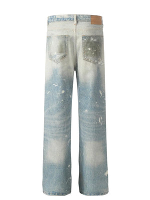 Distressed wash wide leg denim jeans in medium with paint splatter details and ripped pockets.