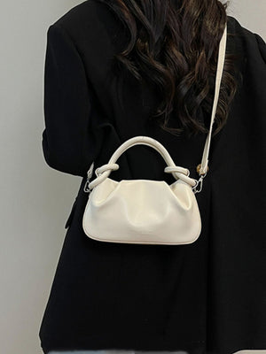 Off-white ruched crossbody bag with knot handle and adjustable strap.