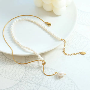 Gold asymmetrical pearl lariat necklace with adjustable chain and single pearl drop.