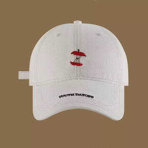 Cream white baseball cap with red apple core embroidery and black text detail