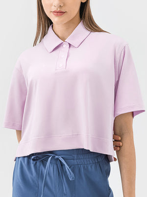 Cropped blush pink polo top with short sleeves and button placket.
