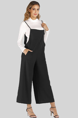 Black culotte overalls with slender straps and wide legs, styled with a white turtleneck.