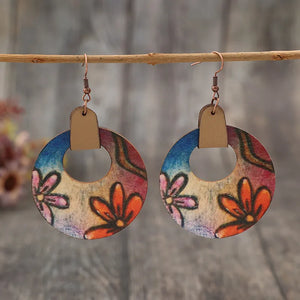 Painted floral wood hoop earrings in orange with artistic blooms and leather accents.