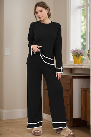 Black loungewear set with round neck top and wide leg pants, featuring white piping detail.