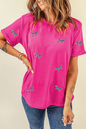 Hot pink t-shirt with allover embroidered bow details and rolled sleeves.
