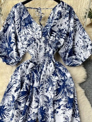 Tropical print smocked wide-leg romper in Dark Blue with V-neck and tie detail.