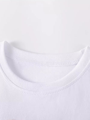 White baby dress neckline detail, cotton fabric with rainbow heart applique.