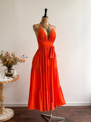 Orange tiered maxi dress with plunging V-neck, cinched waist, and halter straps.