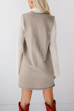 Sleeveless knit dress in camel with V-neck, layered over a striped long-sleeve top.