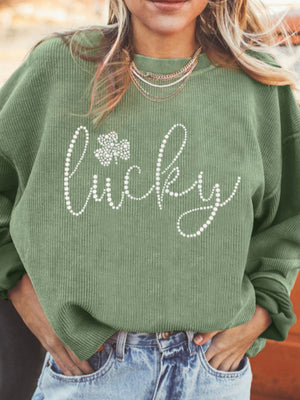 Sage corduroy sweatshirt with white beaded "lucky" and shamrock graphic.
