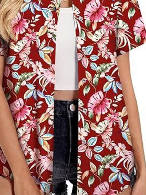 Red tropical hibiscus print button-up shirt with short sleeves, styled open over a white crop top and denim shorts.
