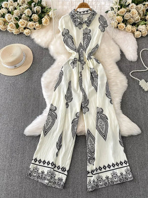 White wide leg romper with black paisley print, collared, button-down front, and cinched waist.