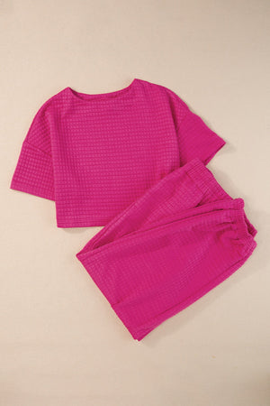 Hot pink quilted knit crop top and jogger set with crew neck and short sleeves.