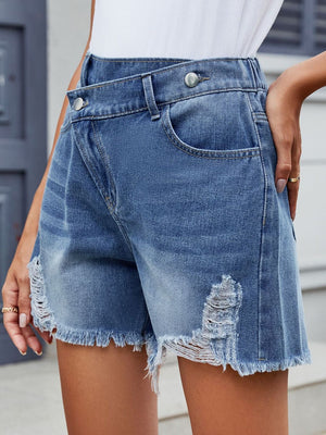 Medium wash denim shorts with asymmetric wrap, shredding and frayed hem.