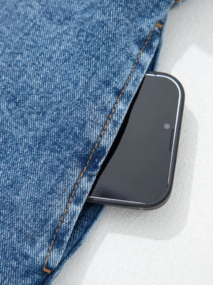 Belted denim dress pocket detail with a smartphone.