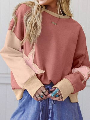 Dusty pink sweatshirt with star patchwork, exposed seams, and contrast stitching.