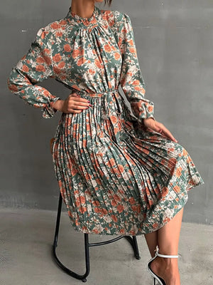 Green floral midi dress with pleated skirt, ruffled mock neck, and long sleeves.