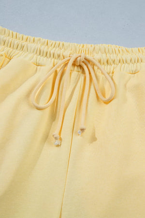 Yellow cotton drawstring pants with elastic waistband and tie detail.