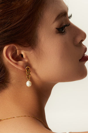 Gold chunky chain and pearl drop earrings with a modern, bold design.