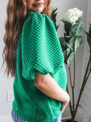 Diamond quilted puff sleeve top in turquoise with textured fabric and voluminous sleeves.