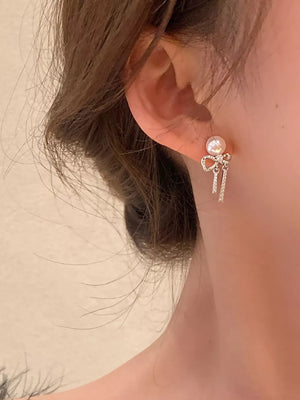 Luminous bowknot pearl drop earrings with crystal accents.