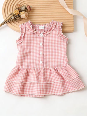 Blush pink gingham baby dress with ruffled neckline and tiered skirt.