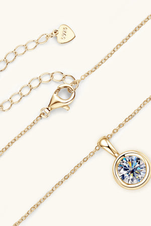 Gold solitaire pendant necklace with bezel-set crystal and adjustable chain with lobster clasp.