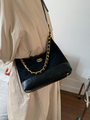 Black crossbody bag with chain detail and quilted bottom panel.
