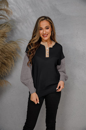 Colorblock henley sweater in black and grey acrylic with button detail and tan neckline.