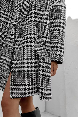 Oversized houndstooth cocoon coat in black and white with double-breasted closure and side slit.