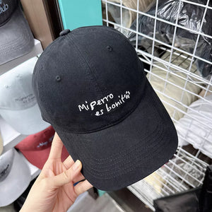 Black baseball cap with "Mi perro es boniti" embroidery and paw print detail.