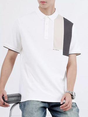 White cotton polo shirt with asymmetrical color-block detail on shoulder and black trim sleeves.