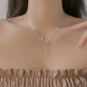 Sterling silver Y-necklace with delicate heart charms, resting on the collarbone.